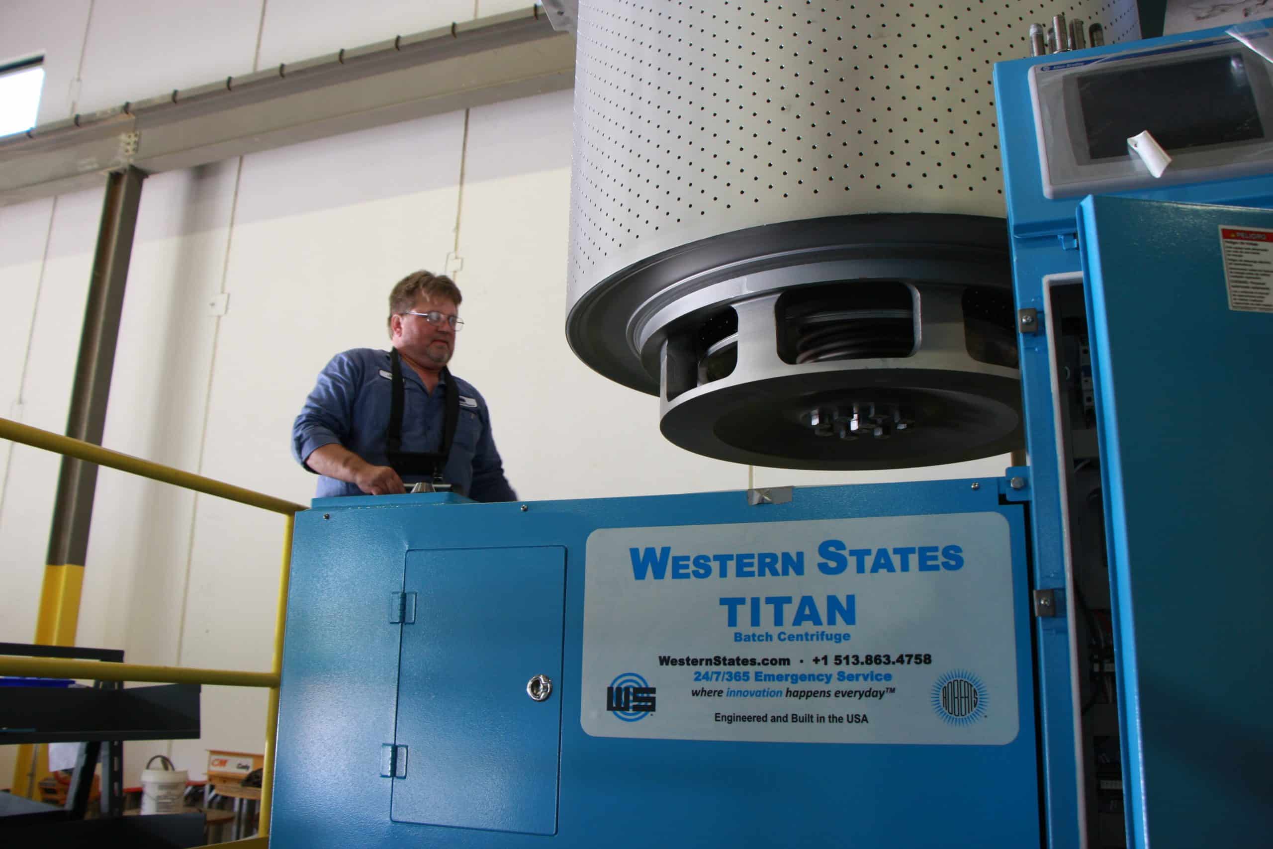 External view of Western States Titan batch centrifuge operated by an employee with safety harness on.