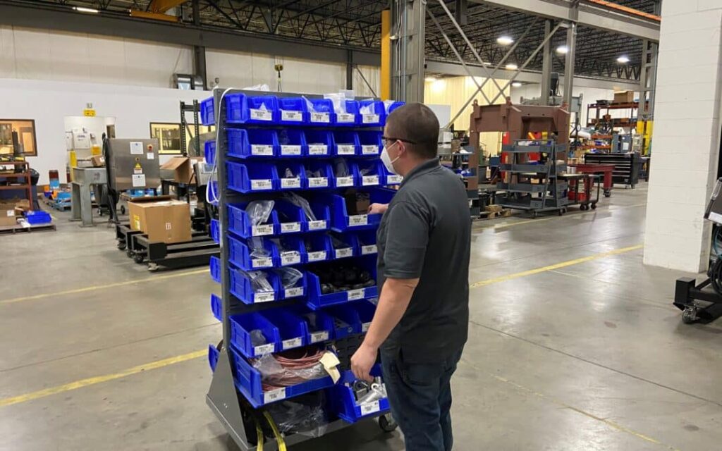 Western States Machine shop employee searching for parts in a elevated blue parts bin